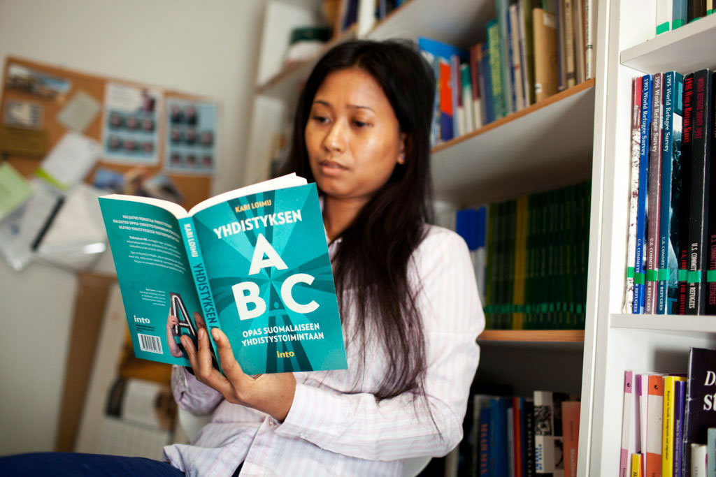 Nainen lukee kirjaa nimeltä Yhdistylsen ABC, Opas suomalaiseen yhdistystoimintaan.