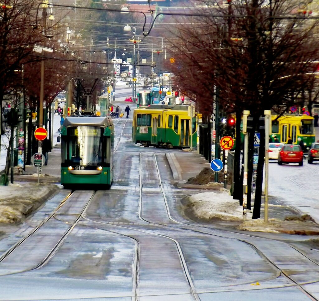Kuvassa näkyy liikennettä Helsingissä talvisena päivänä. Kuva on otettu raitiovaunukiskoilta. Etäältä on saapumassa raitiovaunu.